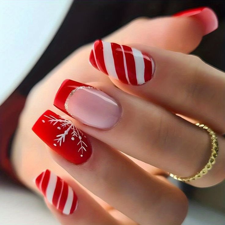 Ongles décorés pour Noël avec des rayures rouges et blanches inspirées des cannes de sucre, accompagnés de motifs de flocons de neige et d'une touche de doré.